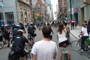 Gebäude säumen eine Straße, auf der einige Menschen Fahrrad fahren.