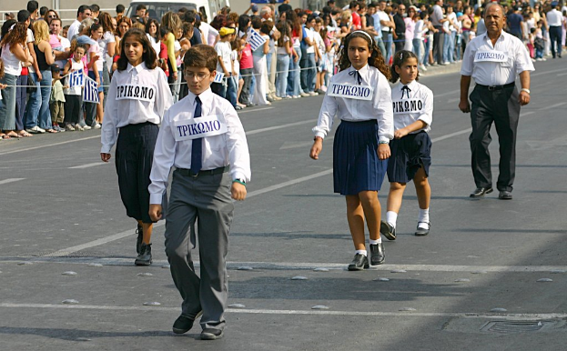 Eine Gruppe von Menschen geht auf einer Straße, trägt Abzeichen auf ihren Hemden, mit einer großen Menge, die sich um die Straße versammelt.