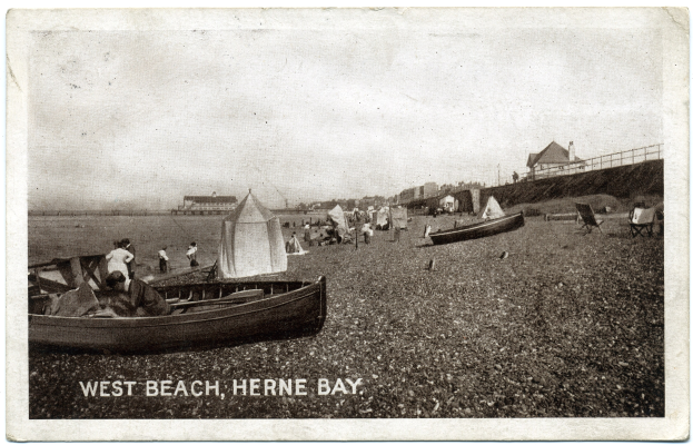 Schwarzes und wei├čes Foto von Menschen am Weststrand, Herne Bay, mit Booten im Vordergrund, H├Ąusern und einem Zaun im Hintergrund und Text am unteren Rand.