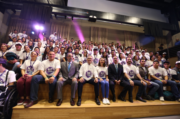 Eine Gruppe von Menschen sitzt auf einer Bühne mit einer Person im Rollstuhl links, mit Vorhängen, Scheinwerfern und einer Wand im Hintergrund auf der Nationalen Konferenz der Frauenbasketball-Vereinigung.