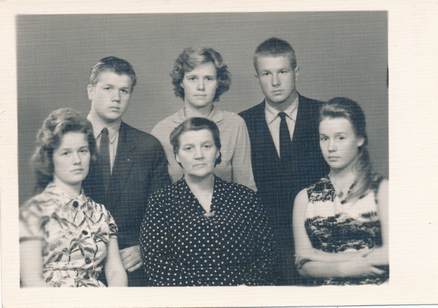 Ein Schwarz-Weiß-Foto einer Familie, die posiert, mit einer Frau in einem Kleid in der Mitte.