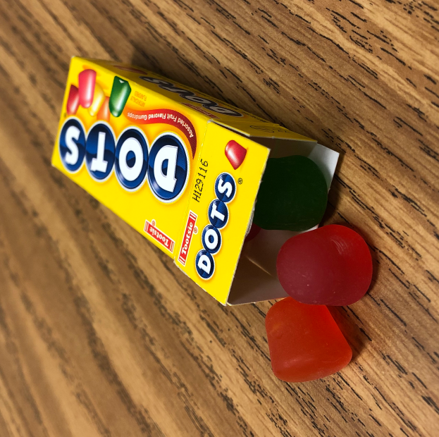 Eine Schachtel mit der Aufschrift "Pünktchen" gefüllt mit bunten Gummibärchen auf einem Holztisch.