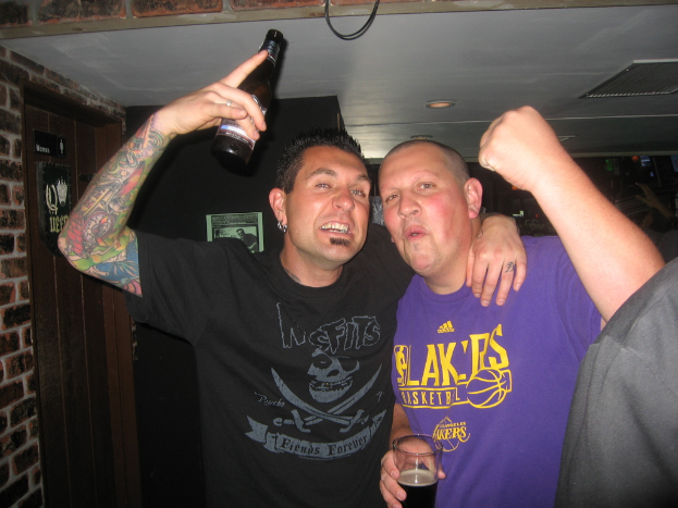 Eine Gruppe von Menschen mit einem Mann, der links ein Bier hält.