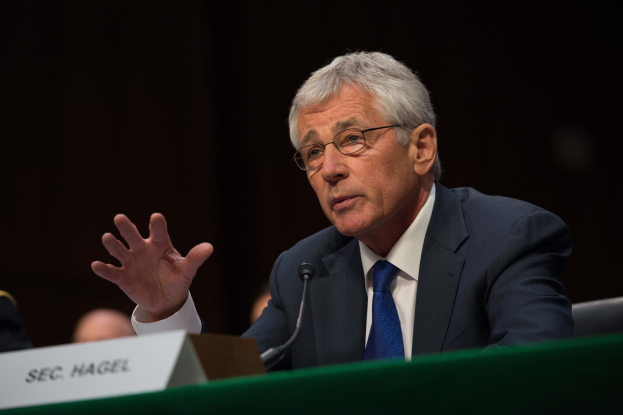 Ein Mann im Anzug und Krawatte sitzt an einem Tisch mit Namensschild und Mikrofon, trägt eine Brille und spricht vor dem Senate Judiciary Committee auf dem Capitol Hill, mit dunklem Hintergrund und wenigen anderen Personen.